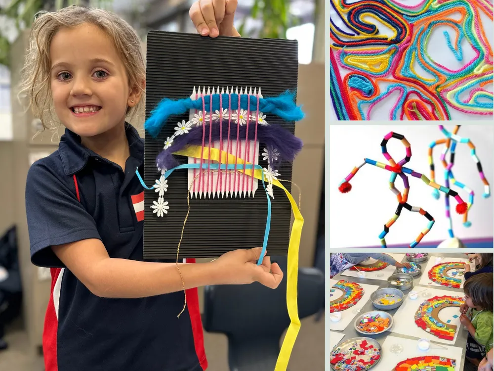 A child holding a piece of art and craft and smiling