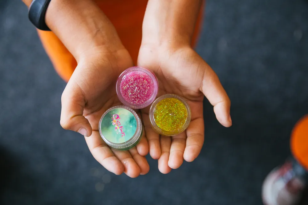 hands holding colourful body glitter containers