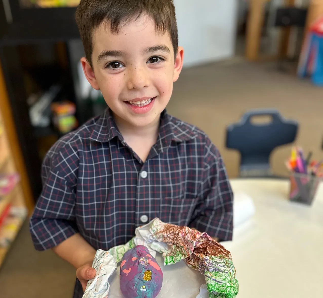 A child smiling and holding an art piece