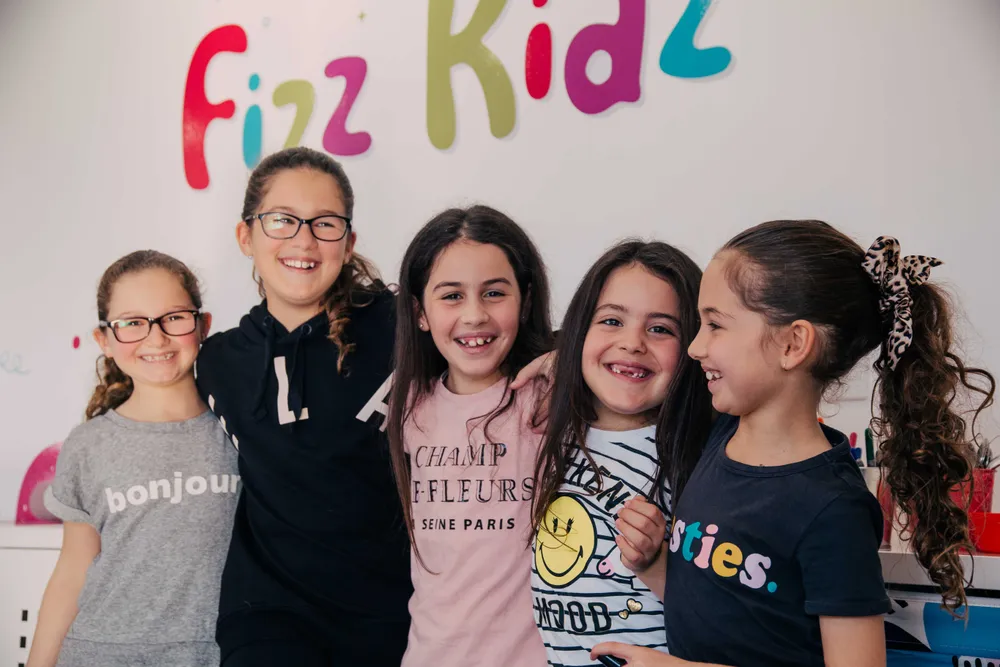 Kids smiling under a Fizz Kids logo