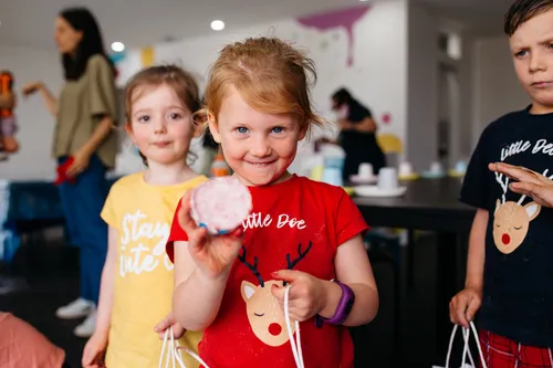 A child holding a bath bomb and smiling at the camera