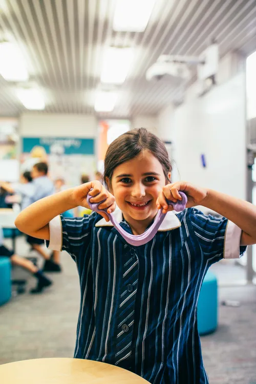 smiling child holding up slime