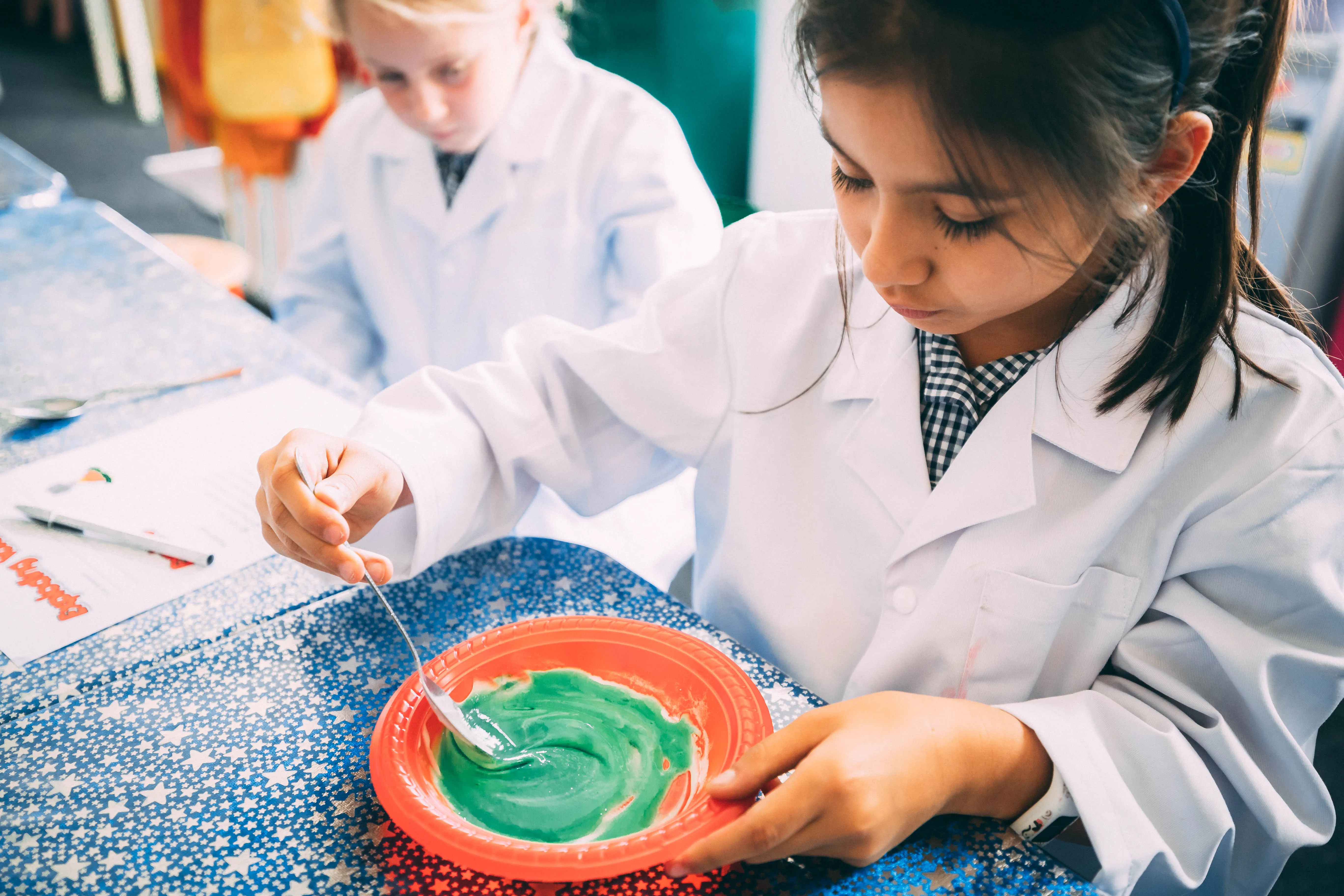 A child in a lab coat carefully mixing their experiment