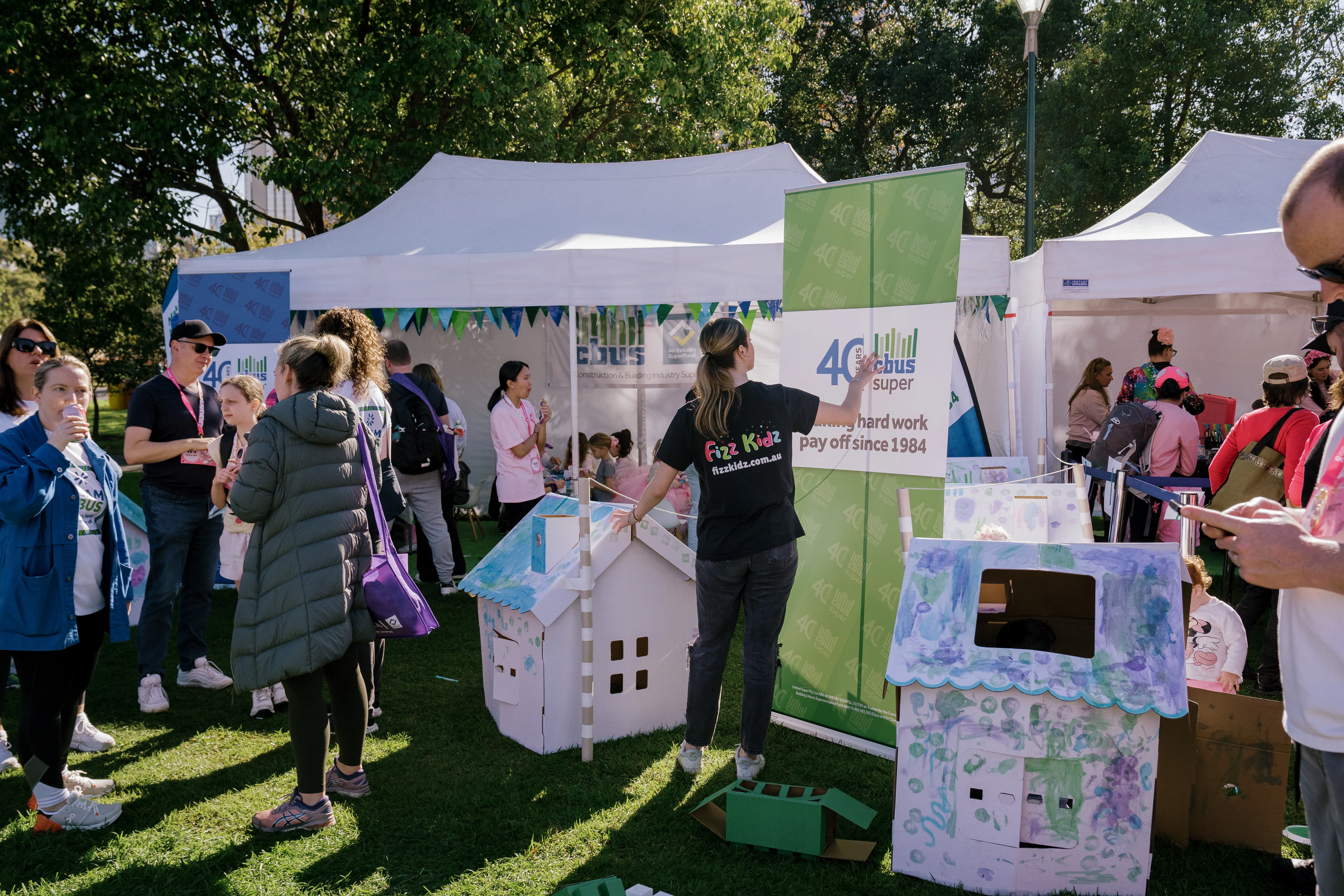 Fizz Kids building cardboard houses outdoors with a marquee in the background