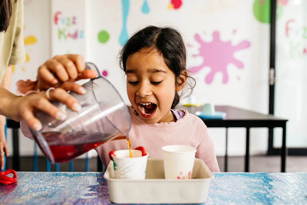 a kid in awe as her science experiment bubbles