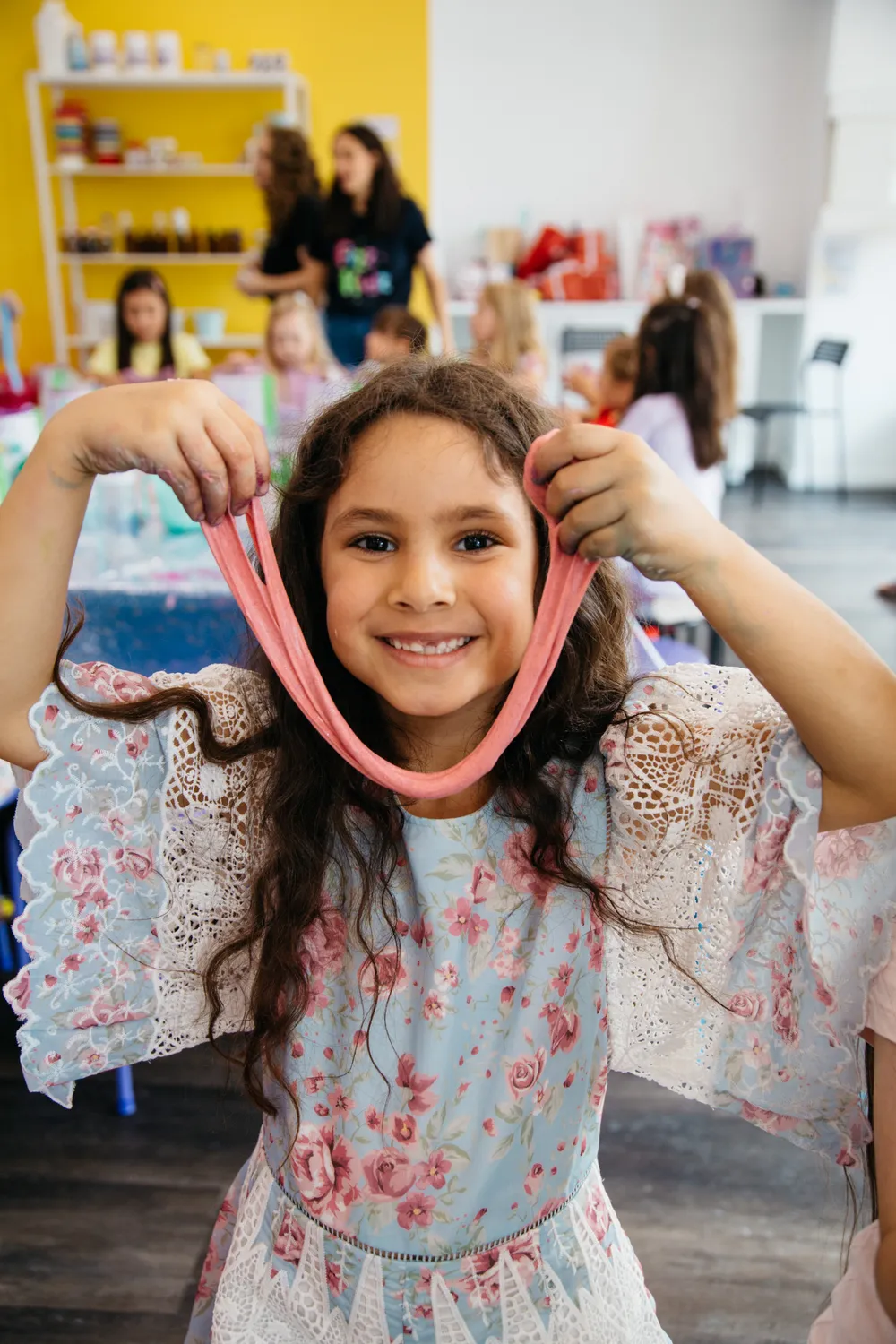 a kid holding a long stretch of slime and smiling